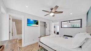 A modern hotel room with a bed, a ceiling fan, a large window, and a view of a beach. - Tropical Paradise+ Pool & Patio! (Fort Lauderdale)
