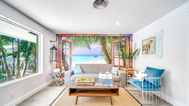 A modern living room with a beach view, a sofa, a coffee table, and a baby crib. - Tropical Paradise + Pool & PATIO (Fort Lauderdale)