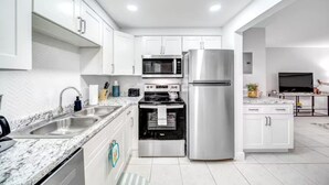 A modern kitchen with white cabinets, stainless steel appliances, a granite countertop, and a built-in oven. - Tropical Paradise + POOL & PATIO (Fort Lauderdale)