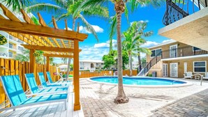 A pool area with lounge chairs, a wooden deck, and a palm tree. - Tropical Paradise + POOL & PATIO (Fort Lauderdale)