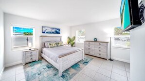 A bedroom with a bed, a dresser, a nightstand, a window with blinds, and a painting on the wall. - Tropical Paradise + POOL & PATIO (Fort Lauderdale)