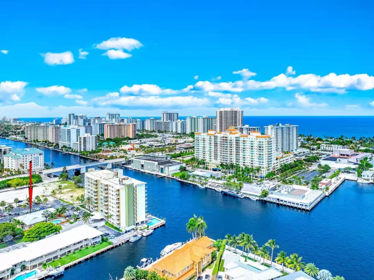 A coastal cityscape with high-rise buildings, a marina, and a clear blue sky.