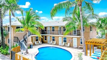 A pool area with a circular pool, lounge chairs, and palm trees.