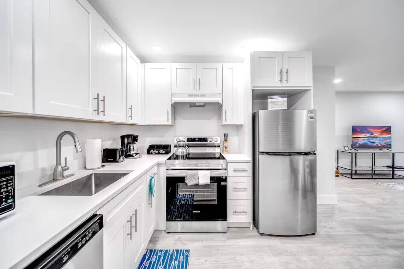 A modern kitchen with white cabinets, stainless steel appliances, and a built-in oven.