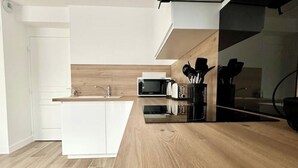 A modern kitchen with a wooden countertop, white cabinetry, and a microwave. - Bienvenue Chez Annabelle - Meaux (Meaux)