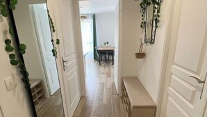 A hallway with a bench, a mirror, and a dining area in the background. - Bienvenue Chez Annabelle - Meaux (Meaux)