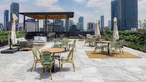 Eine Dachterrasse mit Außenbestuhlung, darunter Tische, Stühle und Sonnenschirme.