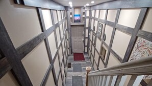 Un escalier étroit avec une rampe en bois et un tapis rouge au bas.