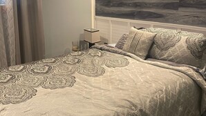 Une chambre à coucher avec un lit, des rideaux, une lampe de chevet et une tête de lit en bois.