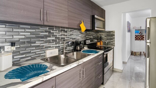 Una cocina moderna con armarios de madera oscura, un lavamanos de acero inoxidable y un microondas.