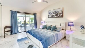 A bedroom with a bed, a chair, a desk, and a ceiling fan.