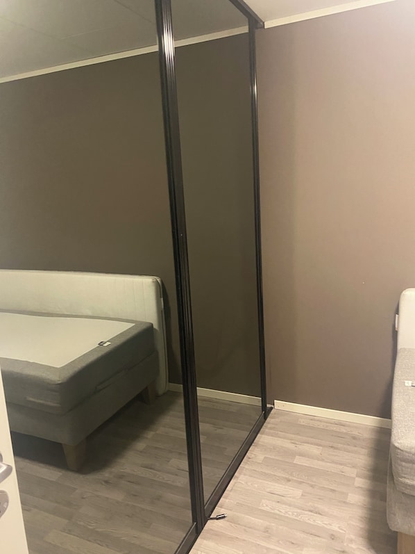 Un dormitorio con cama, armario y puerta con marco negro.