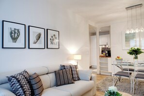 A modern living room with a sofa, a dining table with chairs, and framed artwork on the wall. - Paris Sevigne Elegant residence (Paris)