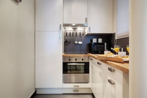 A modern kitchen with white cabinets, stainless steel appliances, and a wooden countertop. - Paris Sevigne Elegant residence (Paris)