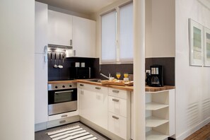 A modern kitchen with white cabinets, a wooden countertop, and a coffee maker. - Paris Sevigne Elegant residence (Paris)