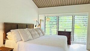 Ein geräumiges Schlafzimmer mit einem großen Bett, Holzboden und Blick durch eine Glastür.