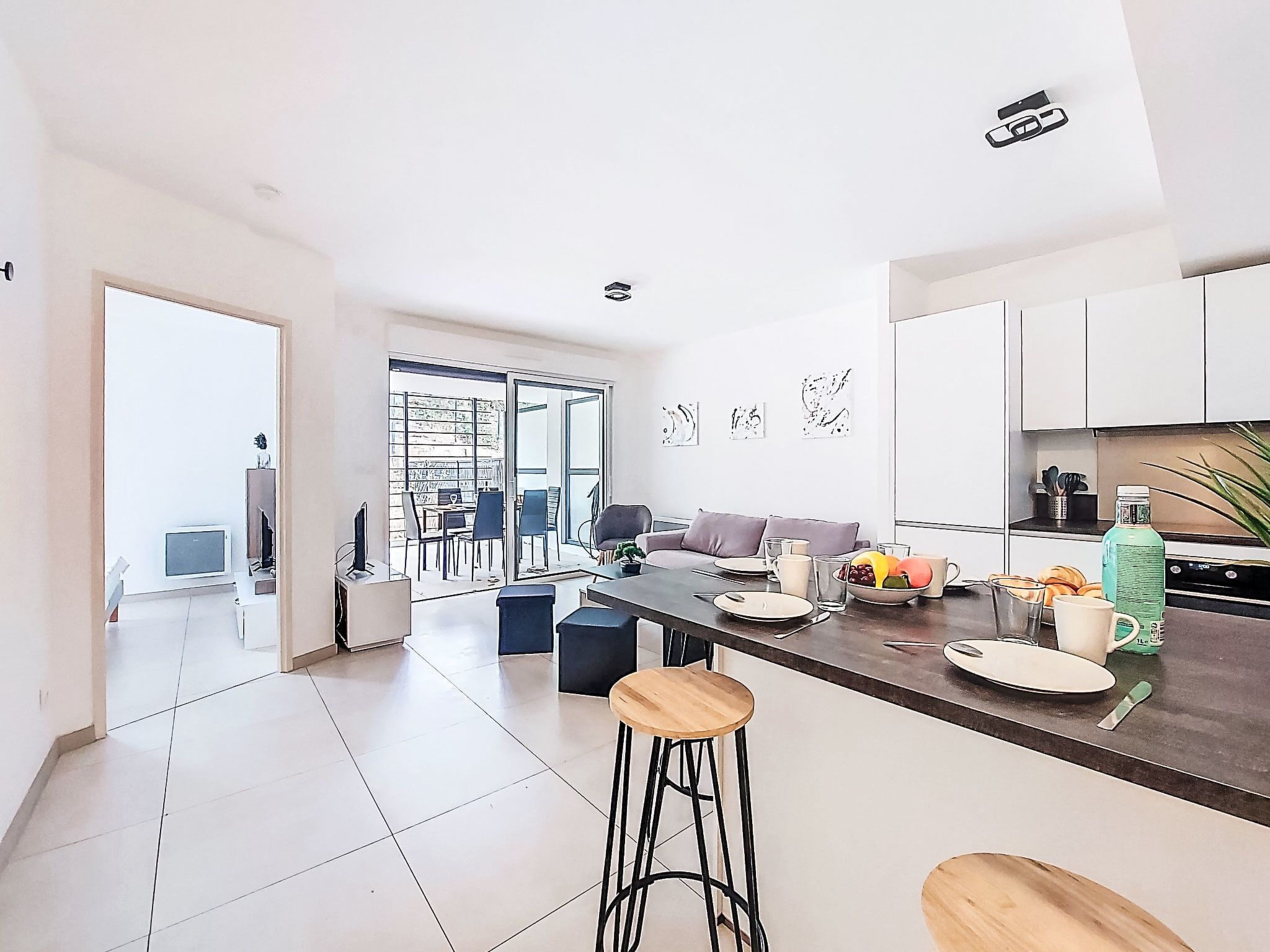 A modern kitchen with a central island, bar stools, and a dining area with a sofa and chairs.