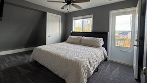 A bedroom with a bed, a ceiling fan, a window, and a door. - 4- Bedroom Retreat with Sauna, Game Room, Patio & Walk to Bars & Restaurants (Sheboygan)