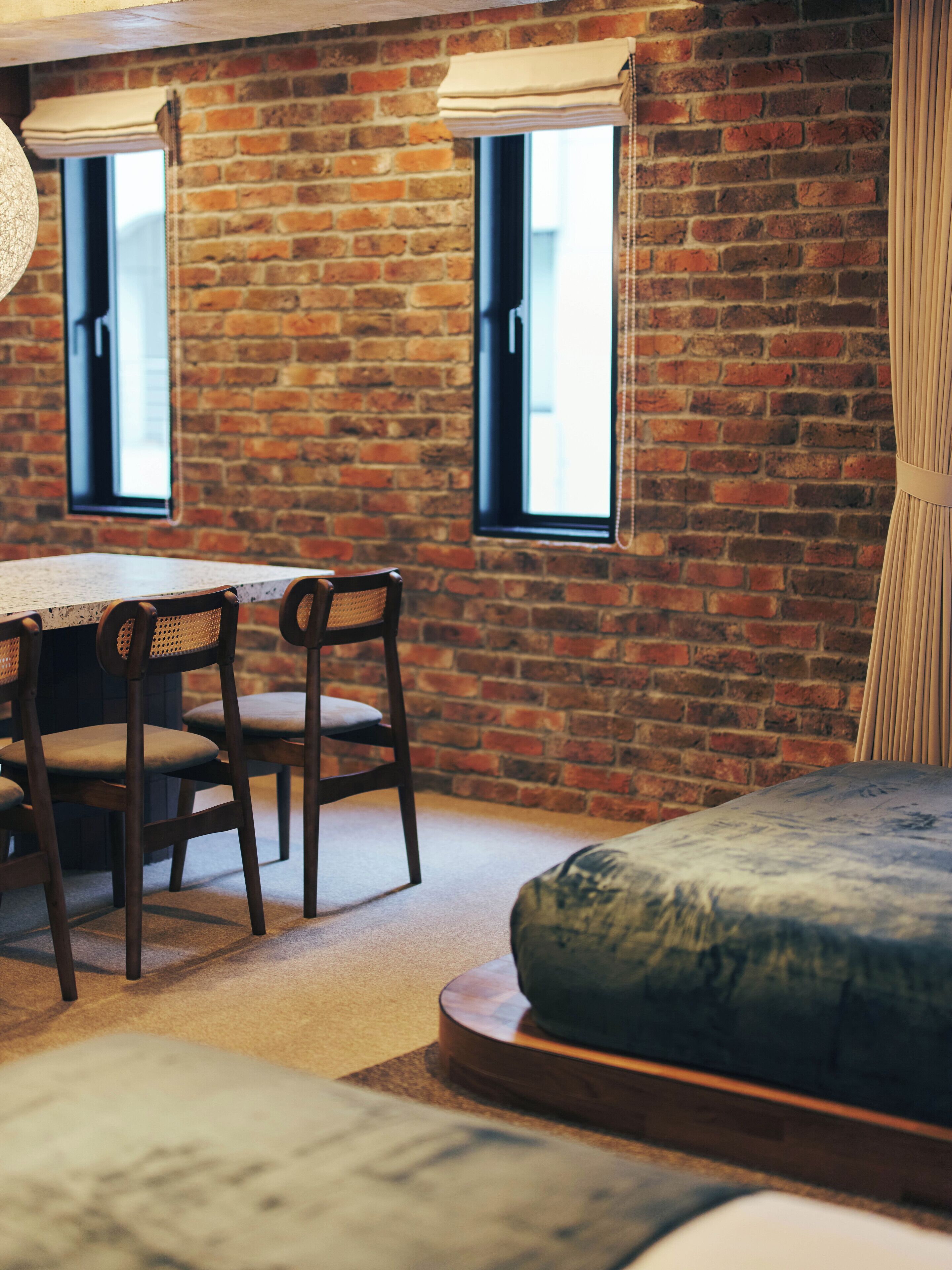 A room with a brick wall, a wooden table with chairs, and a blue sofa.