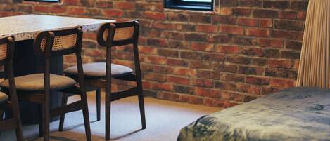 A room with a brick wall, a wooden table with chairs, and a blue sofa.