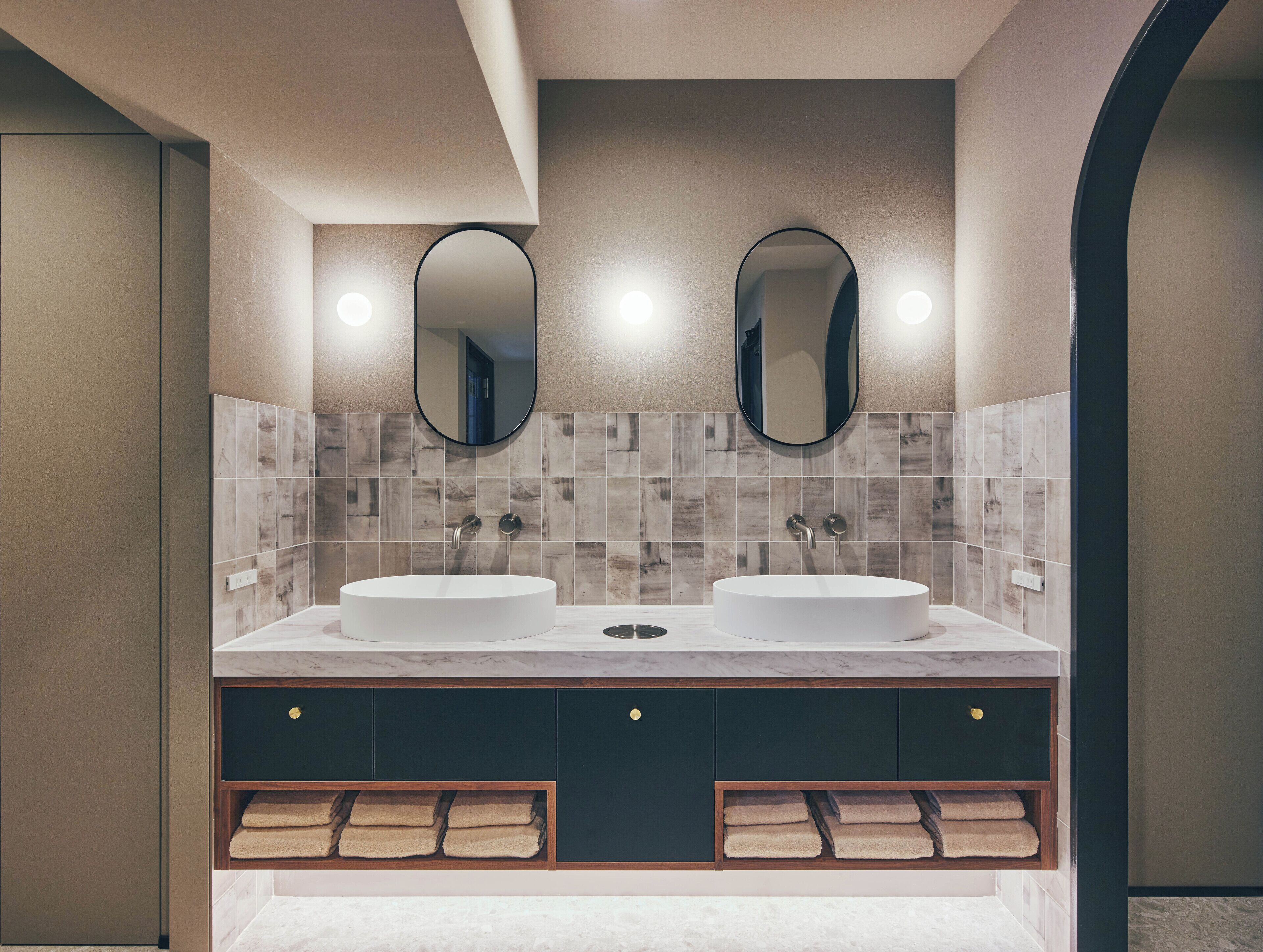 A modern bathroom with two sinks, a vanity with dark cabinets, and a tiled backsplash.