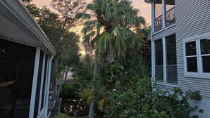 A residential area with a tall palm tree, a house with a balcony, and a grassy yard. - Weeki Wachee Waterfront Canal home. Manatee Manor (Spring Hill)