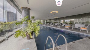 An indoor swimming pool with lounge chairs and potted plants. - Apt with Reforma View - Pool and Jacuzzi (Mexico City)