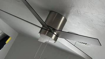 A ceiling fan with a metallic finish, a window with blinds, and a textured ceiling.