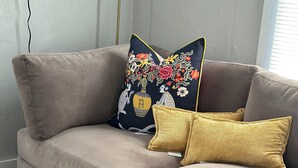 A beige sectional sofa with two decorative pillows, one with a floral pattern and the other in a solid color.
