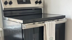 A black and stainless steel oven with four knobs and a digital display.