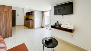 Una sala de estar moderna con televisor, una mesita y una cocina con armarios de madera.