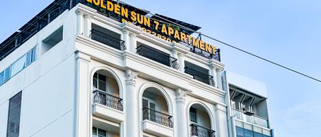A building with a sign reading "GOLDEN SUN APARTMENT."