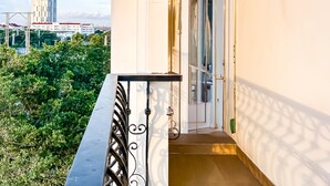 Un balcón con vistas a la ciudad, una puerta de cristal y un pequeño espacio al aire libre con plantas.