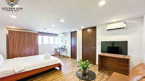 Una habitación de hotel con cama, escritorio, televisor y planta.