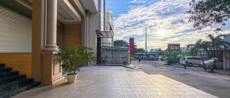 A hotel entrance with a potted plant, a gated entrance, and a clear sky.