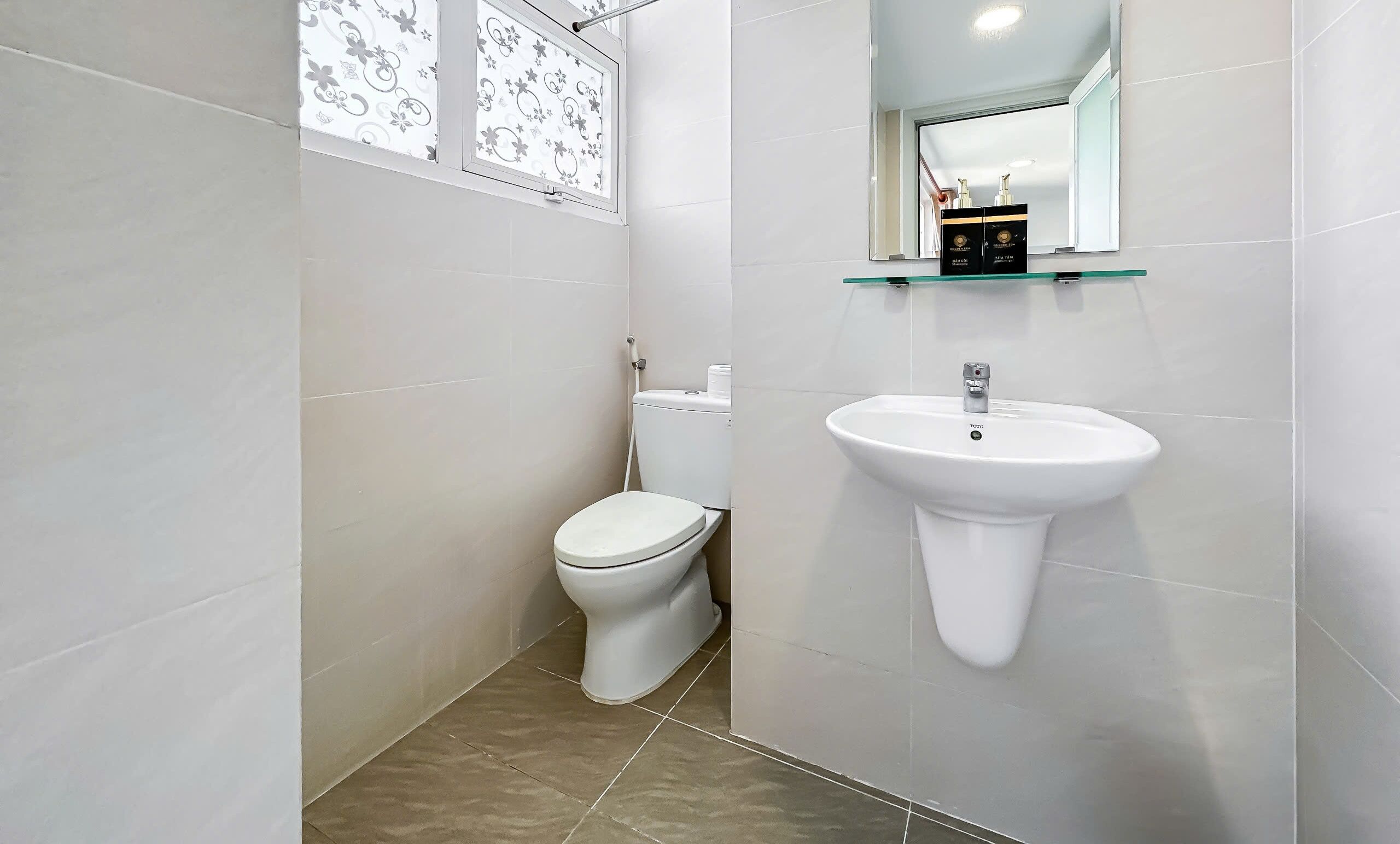 Een compacte, moderne badkamer met toilet, een wastafel op voetstuk en een spiegel boven de wastafel.