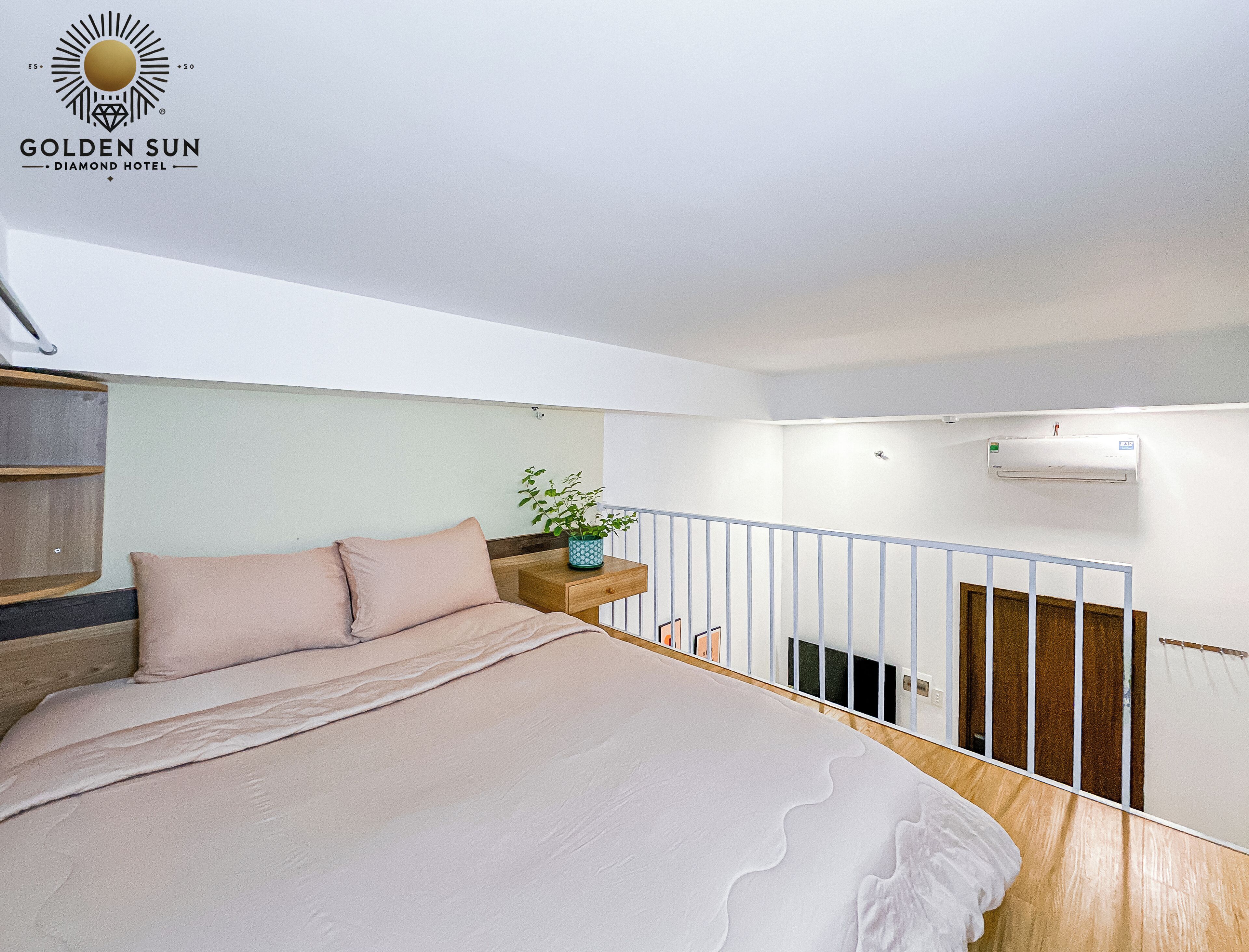 A bedroom with a bed, a nightstand, a potted plant, and a balcony railing.