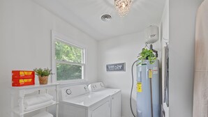 A laundry room with a washer and dryer, a window, a plant, and a sign indicating laundry service. - Spotless Home Near Kings Island (Mason)