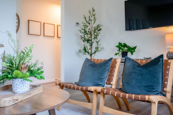 A modern living room with a wooden sofa, a coffee table, and a potted plant. - Spotless Home Near Kings Island (Mason)