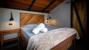 Un lit bien fait, avec une tête de lit en bois, deux lampes de chevet et un banc en bois au pied du lit.