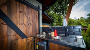 Une cuisine avec des éléments extérieurs en bois, un évier encastré et un réfrigérateur compact.