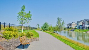 Zona residencial con un camino pavimentado a lo largo de un canal, flanqueada por casas coloridas y una banca.