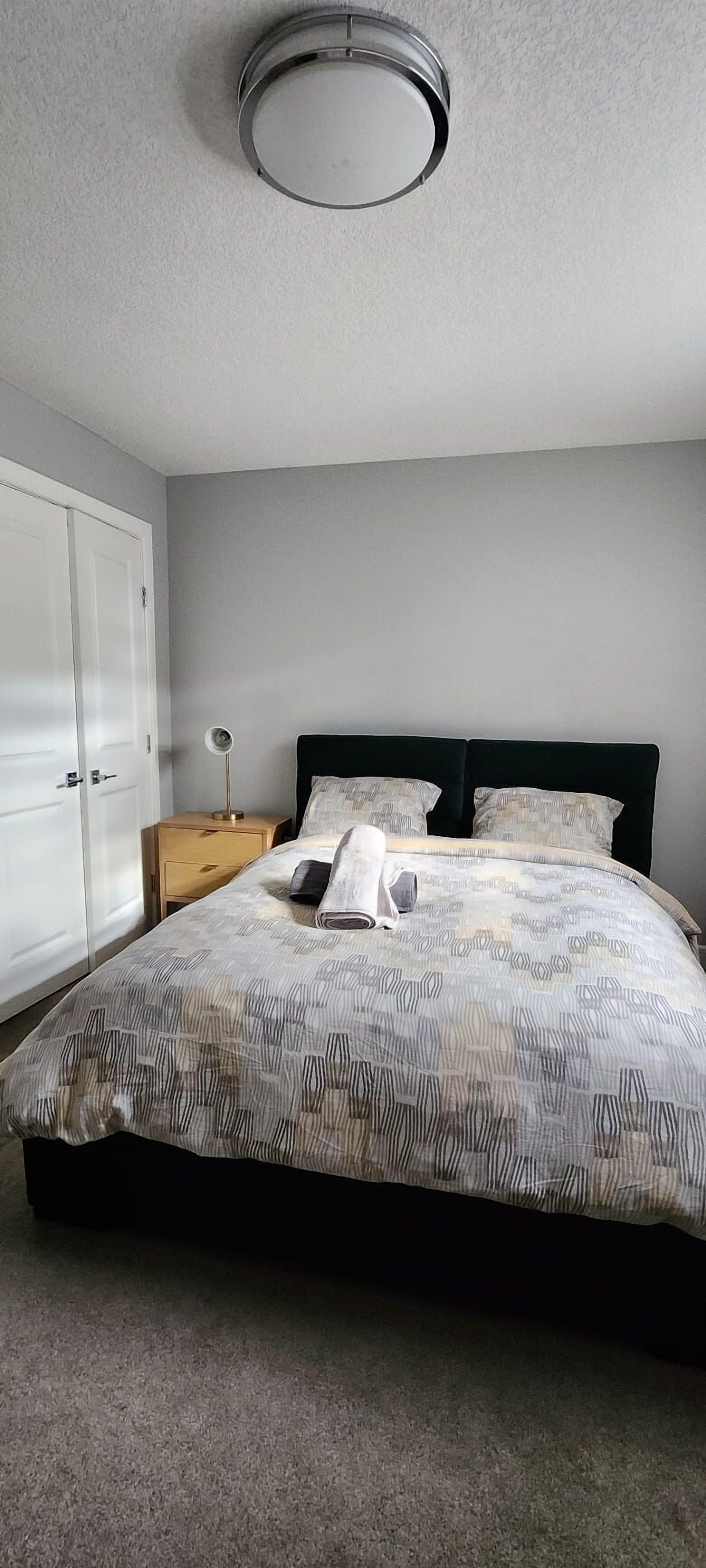 A bedroom with a bed, bedside table, lamp, and wardrobe.