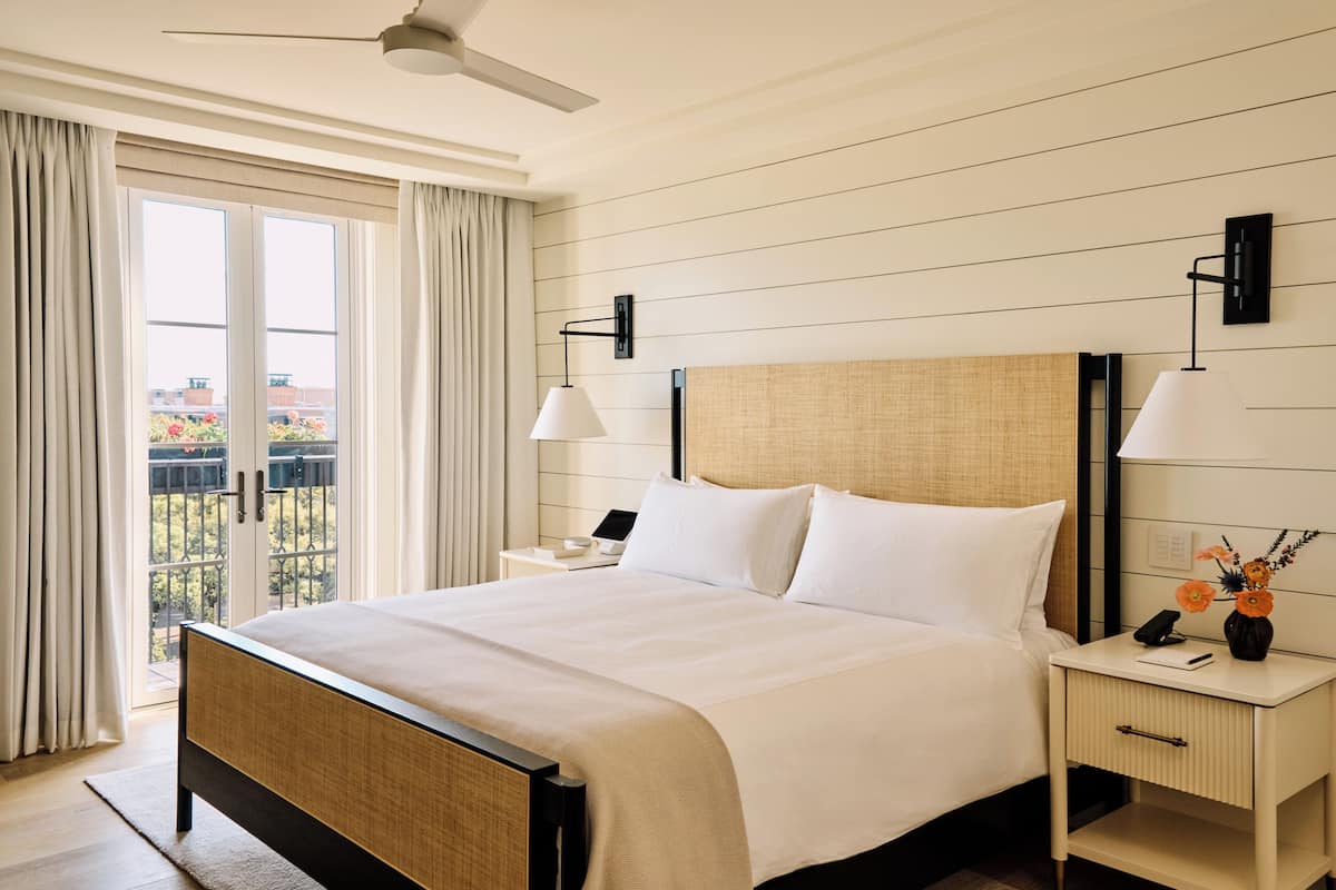 A hotel room with a bed, nightstands, a ceiling fan, and a view through the window.