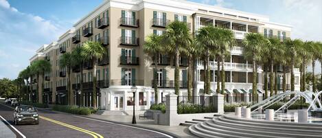 A multi-story hotel with balconies, palm trees, and a fountain.