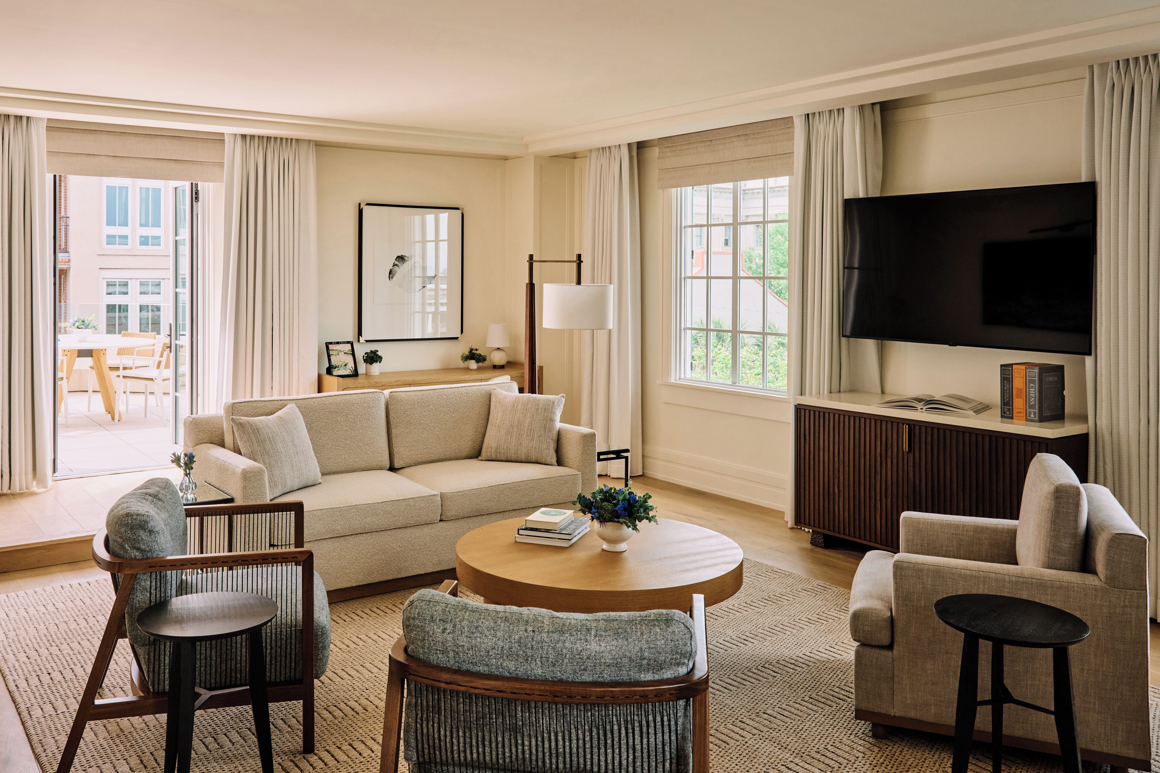 A spacious living room with a sofa, chairs, a coffee table, a TV, and a bookshelf.