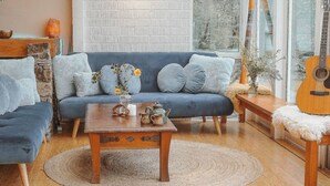 Ein gemütliches Wohnzimmer mit einem blauen Sofa, einem Holztisch und einer Gitarre.