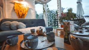 A cozy seating area with a sofa, a table with cups and a teapot, and a Christmas tree in the background.