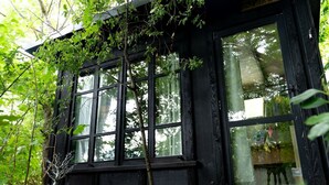 A black building with large windows and a wooden bench in front.
