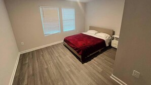 A bedroom with a bed, two bedside tables, and a window with blinds. - Home featuring 3 Rooms 1 Bath Sleeps 6 Guest (Roxboro)